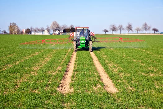 tractor on field sputtering pest protection on plants