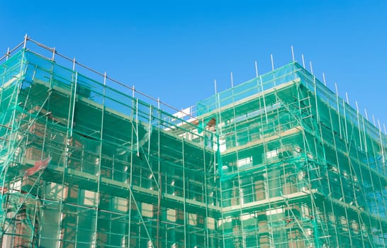 building under construction wrapped in a green net for safety