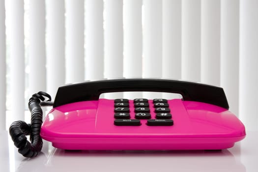 pink office telephone with reflection on the table