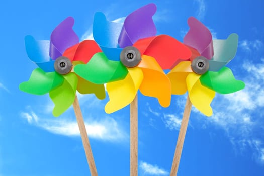 three color pinwheel toys against blue sky