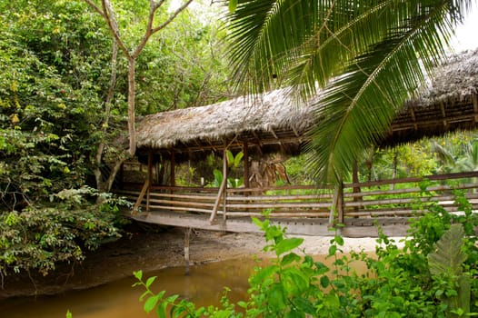 Wooden bridge with roof of straw on a river in Ecuador