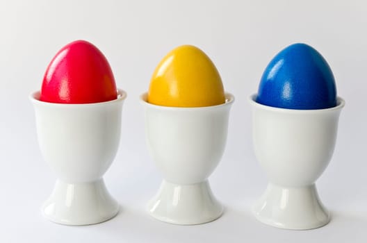 Three colorful eggs in white egg cups