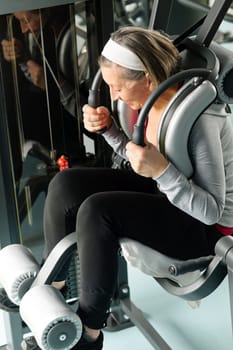 Fitness center senior woman exercise abs muscle on gym machine