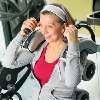 Fitness center senior woman exercise smiling on gym machine