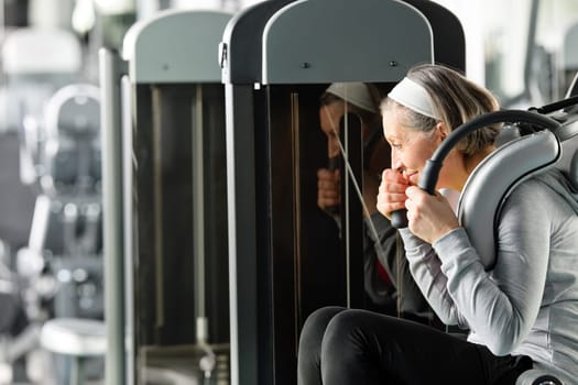 Fitness center senior woman exercise abs muscle on gym machine