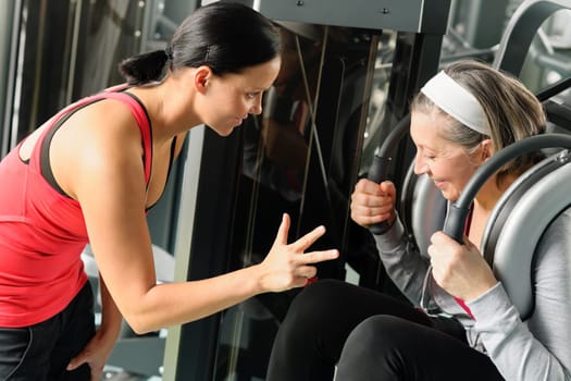 Fitness center senior woman exercise abdominal muscles with personal trainer