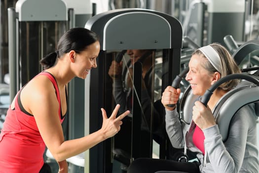 Fitness center senior woman exercise abdominal muscles with personal trainer