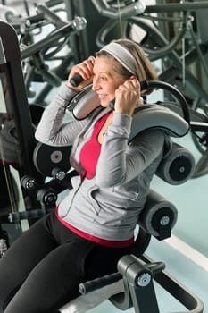Fitness center senior woman exercise smiling on gym machine