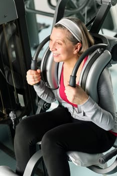 Fitness center senior woman exercise smiling on gym machine