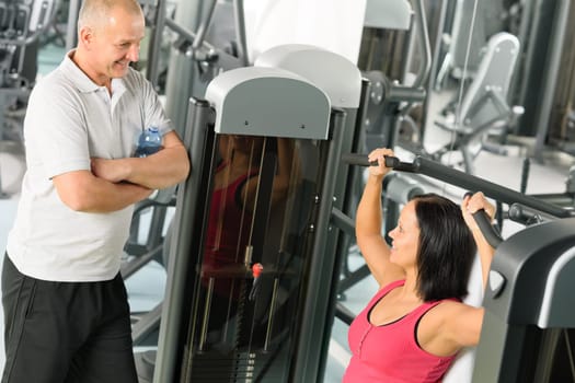 Personal trainer at fitness center showing exercise to active man