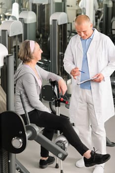 Physical therapist male assist active senior woman exercise at gym