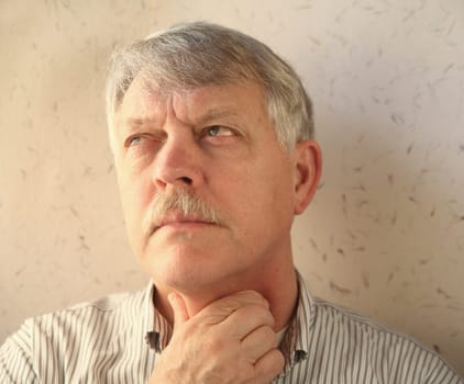 older man rubs his sore throat