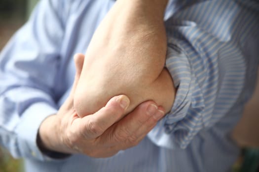 man holds a painful elbow