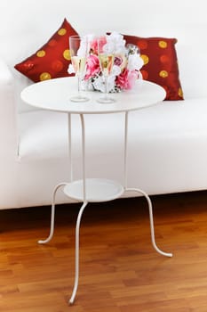 Sparkling wine with bouquet on side table in white