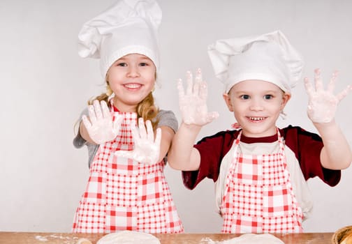 two children in chef&#039 s hats showing the palms