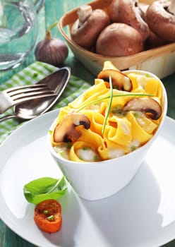 Boat-shaped dish of mushroom tagliatelle with a bowl of fresh mushrooms in the background.