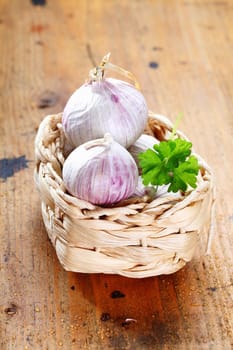 Garlic in a box with parsley on a rustic wooden board