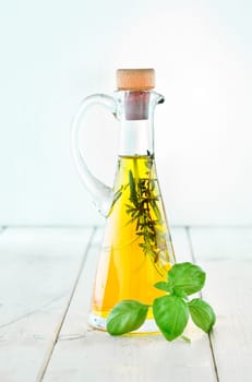 Decanter of Olive Oil with herbs and basil on a wooden plate