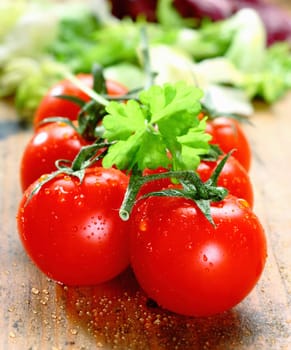 Bunch of fresh red ripe tomatoes with water droplets on rustic wooden boards.