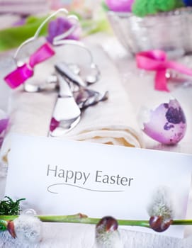 Easter table setting with focus to a plain white card inscribed Happy Easter