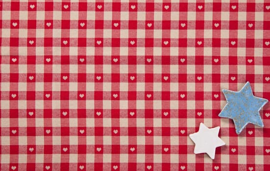 Background of two silver stars lying on colourful fresh red checked fabric with tiny hearts