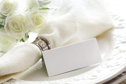 Elegant white Wedding place setting with beautiful white roses and a blank card