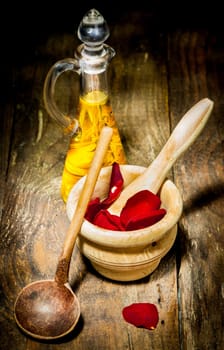 Wellness Care Treatment with rose leaves and ethereal oil on a wooden plate.