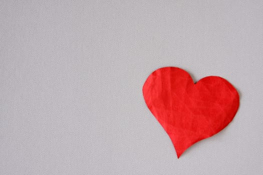 Crumpled red paper heart on a grey background