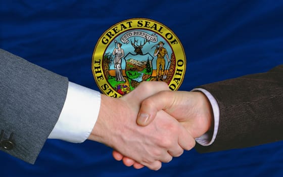 two businessmen shaking hands after good business investment  agreement in america, in front US state flag of idaho