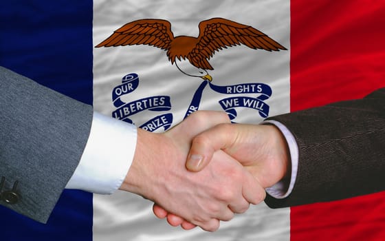 two businessmen shaking hands after good business investment  agreement in america, in front US state flag of iowa