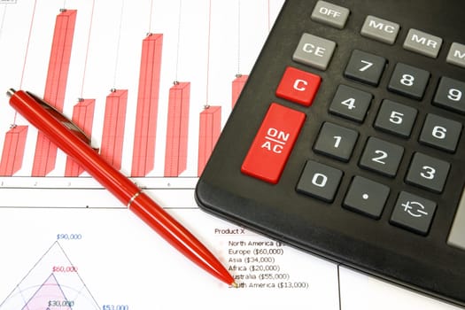 calculator and red pen over a business chart