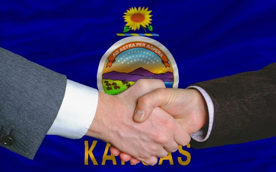 two businessmen shaking hands after good business investment  agreement in kansas, in front US state flag of iowa