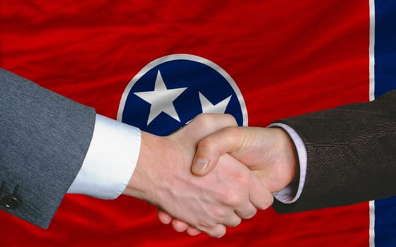 two businessmen shaking hands after good business investment agreement in front US state flag of tennessee