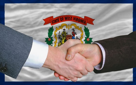 two businessmen shaking hands after good business investment agreement in front US state flag of west virginia