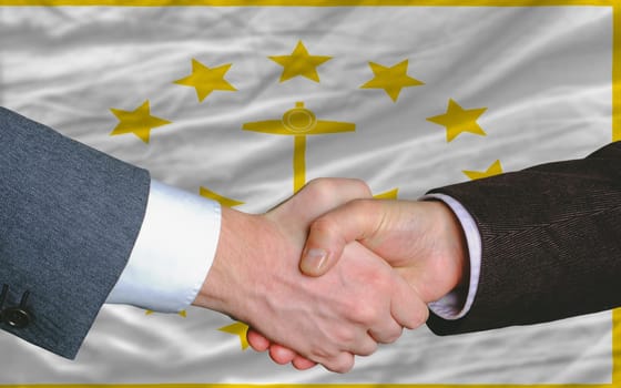 two businessmen shaking hands after good business investment agreement in front US state flag of rhode island