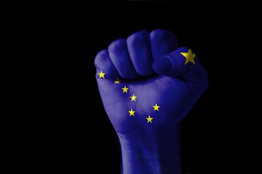 Low key picture of a fist painted in colors of american state flag of alaska