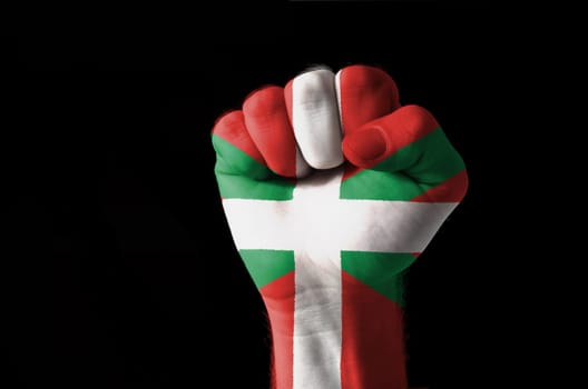 Low key picture of a fist painted in colors of basque flag