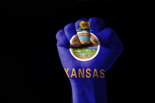 Low key picture of a fist painted in colors of american state flag of kansas
