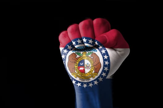 Low key picture of a fist painted in colors of american state flag of missouri