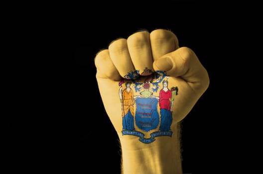 Low key picture of a fist painted in colors of american state flag of new jersey