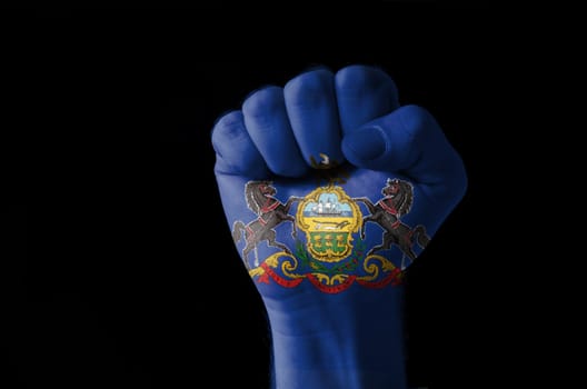 Low key picture of a fist painted in colors of american state flag of pennsylvania