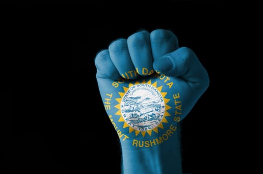 Low key picture of a fist painted in colors of american state flag of south dakota