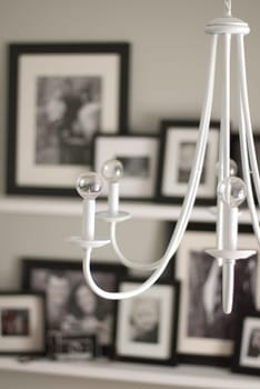 white chandelier hanging in modern house with black and white photos on the wall shallow depth of field portrait view