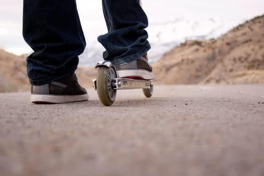 child riding scooter on paved pathway with mountains in background