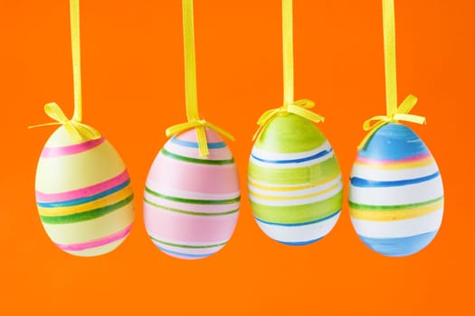 four colorful easter eggs isolated on orange background