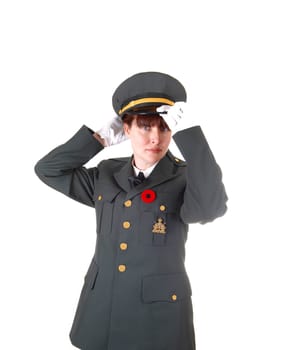 A woman in her forties in a dark olive green uniform standing for white background with white cloves putting her cap on.