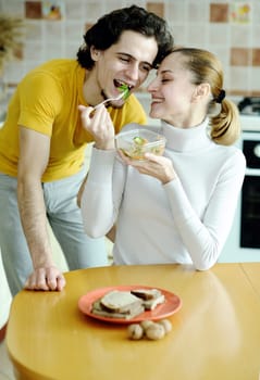 An image of young happy couple eating at kitchen