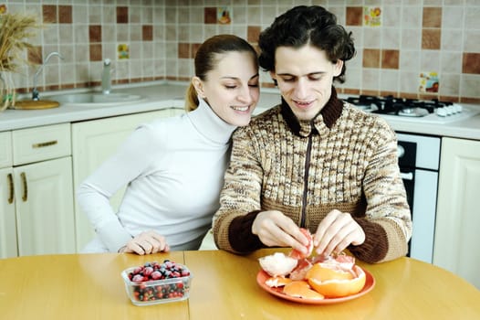 An image of young happy couple eating at kitchen