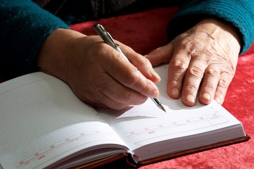 Old hands writing in a notebook