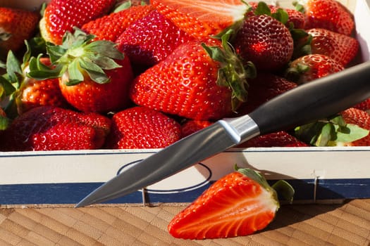 Strawberries in wooden box with knife
